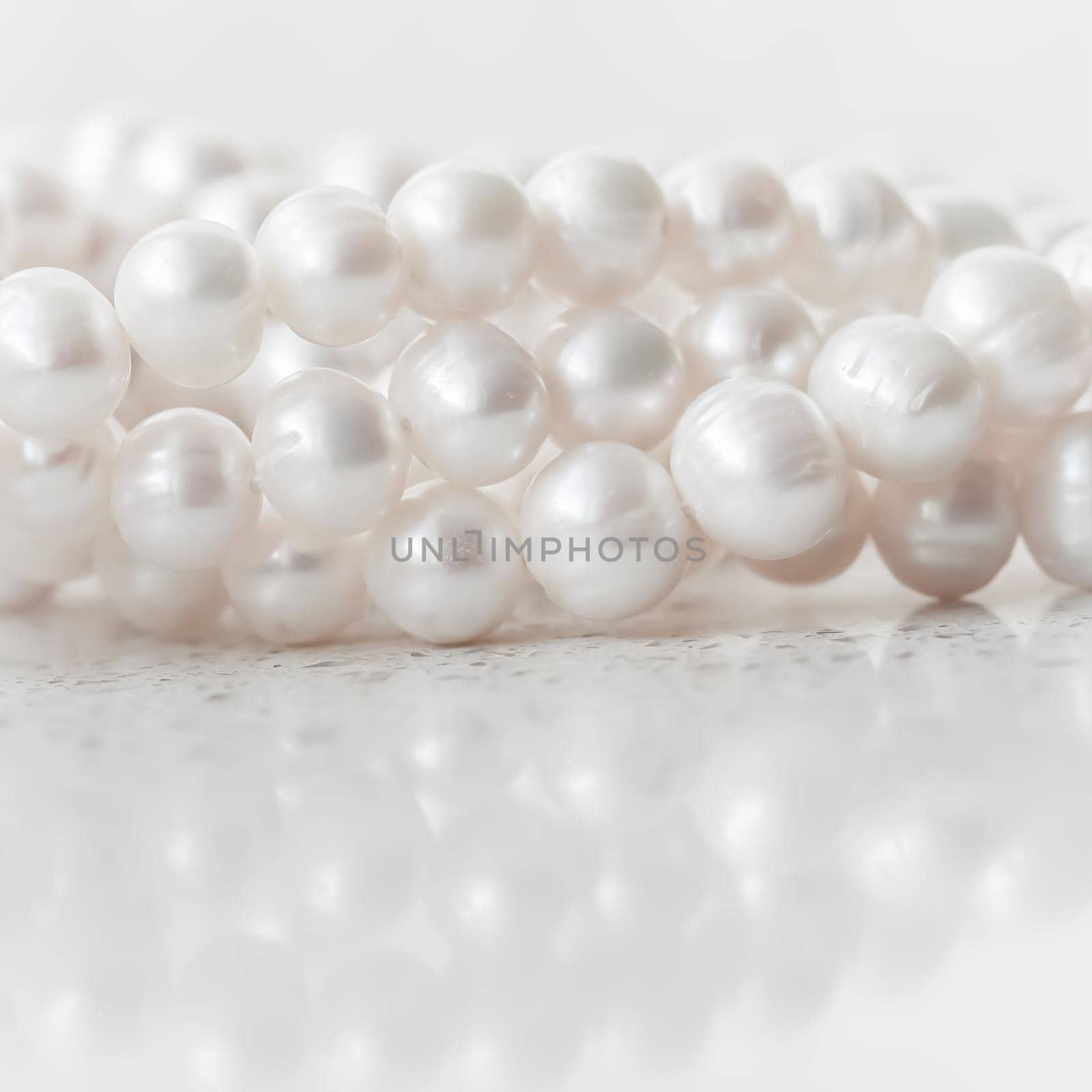 Nature white string of pearls on marble background in soft focus, with highlights