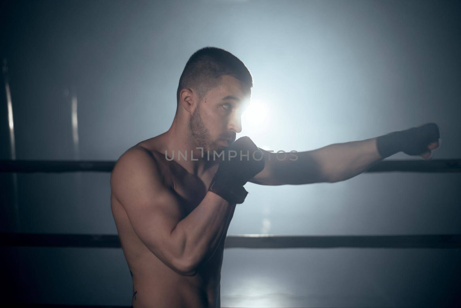 Muscular MMA fighter practicing punch, fight club concept. High quality photo