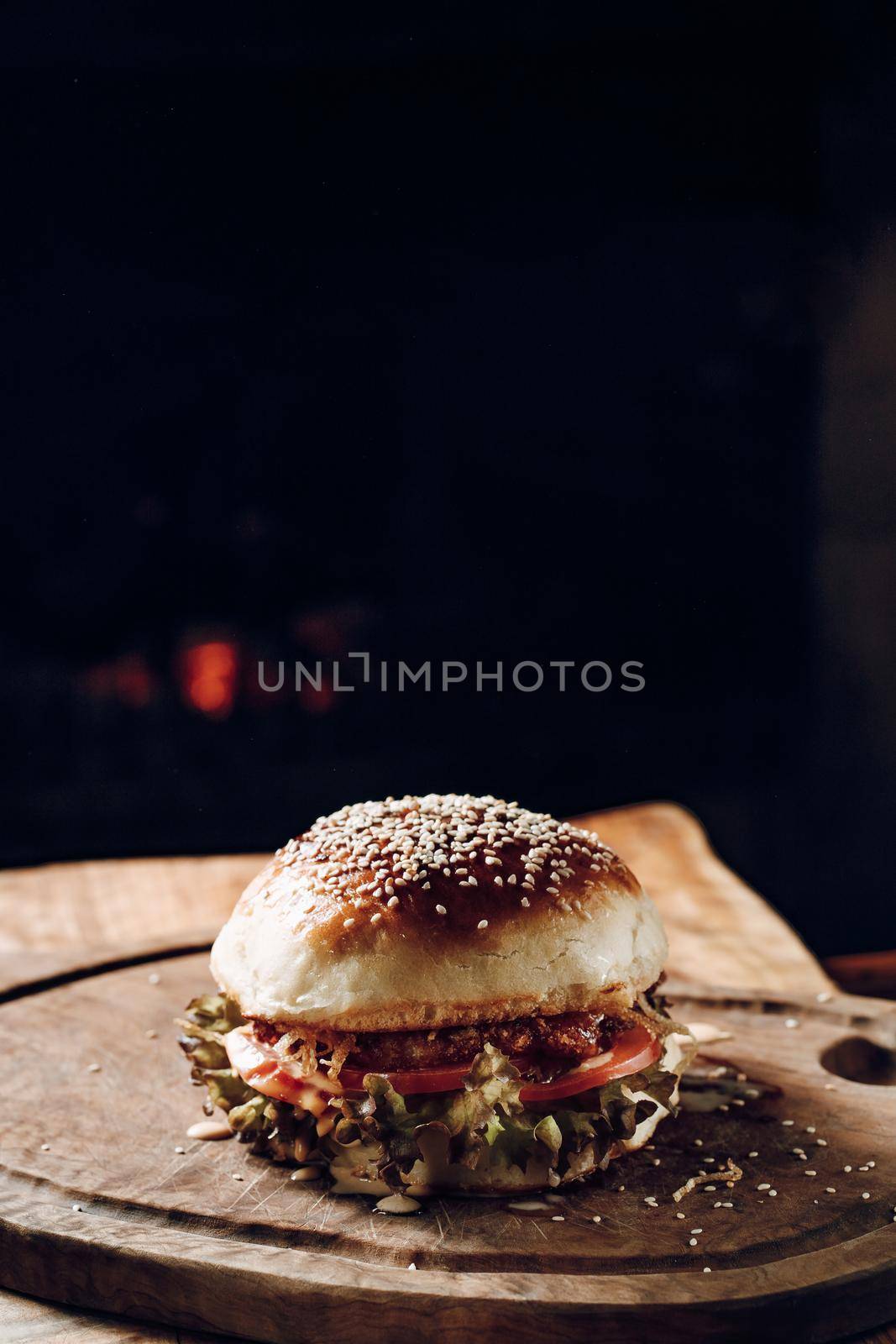 Juicy hamburger on a wooden stand on a black background by Praximon