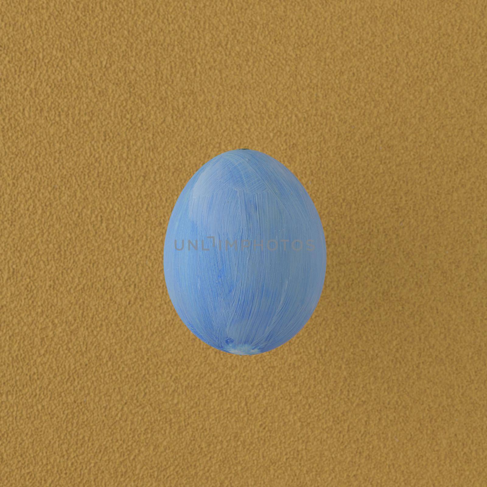 Blue painted egg on yellow background.