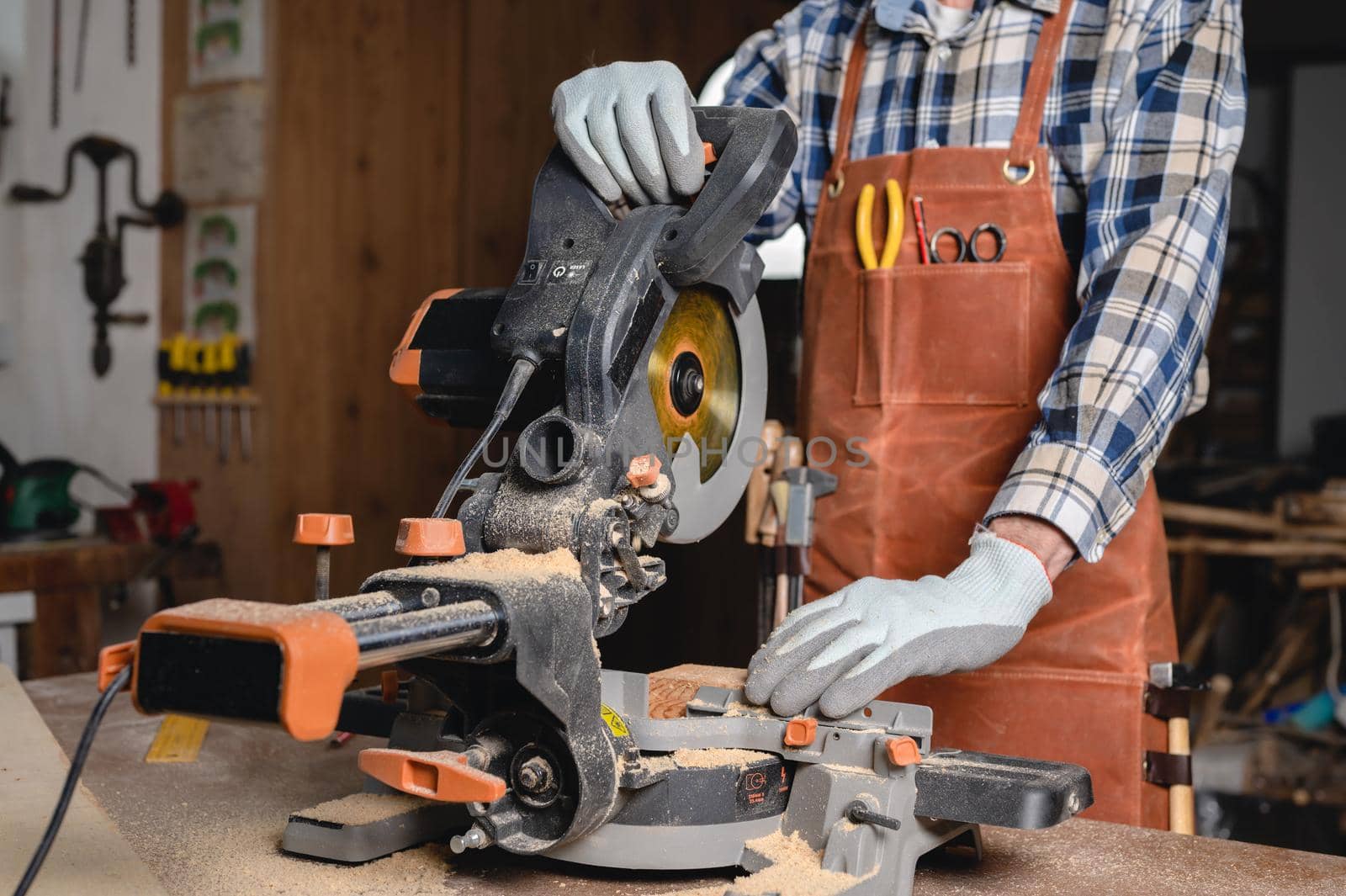 Carpenter using an electric circular saw, cutting piece of wood. by HERRAEZ