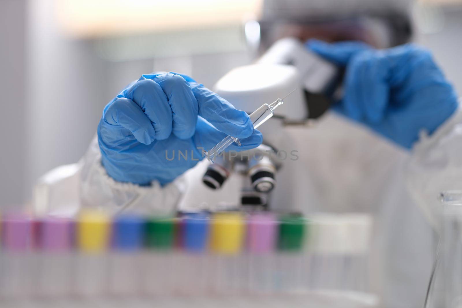 Close-up of scientist in laboratory holding syringe with liquid vaccines. Pharmaceutical bio research. Vaccine development program