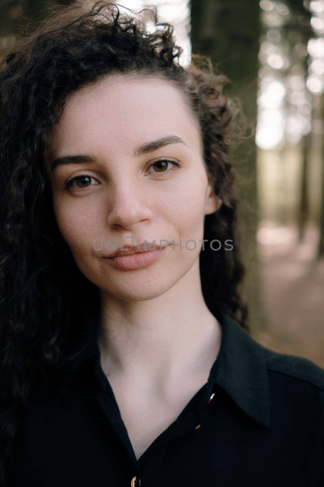 portrait of curly brunette woman in the park close up by Symonenko