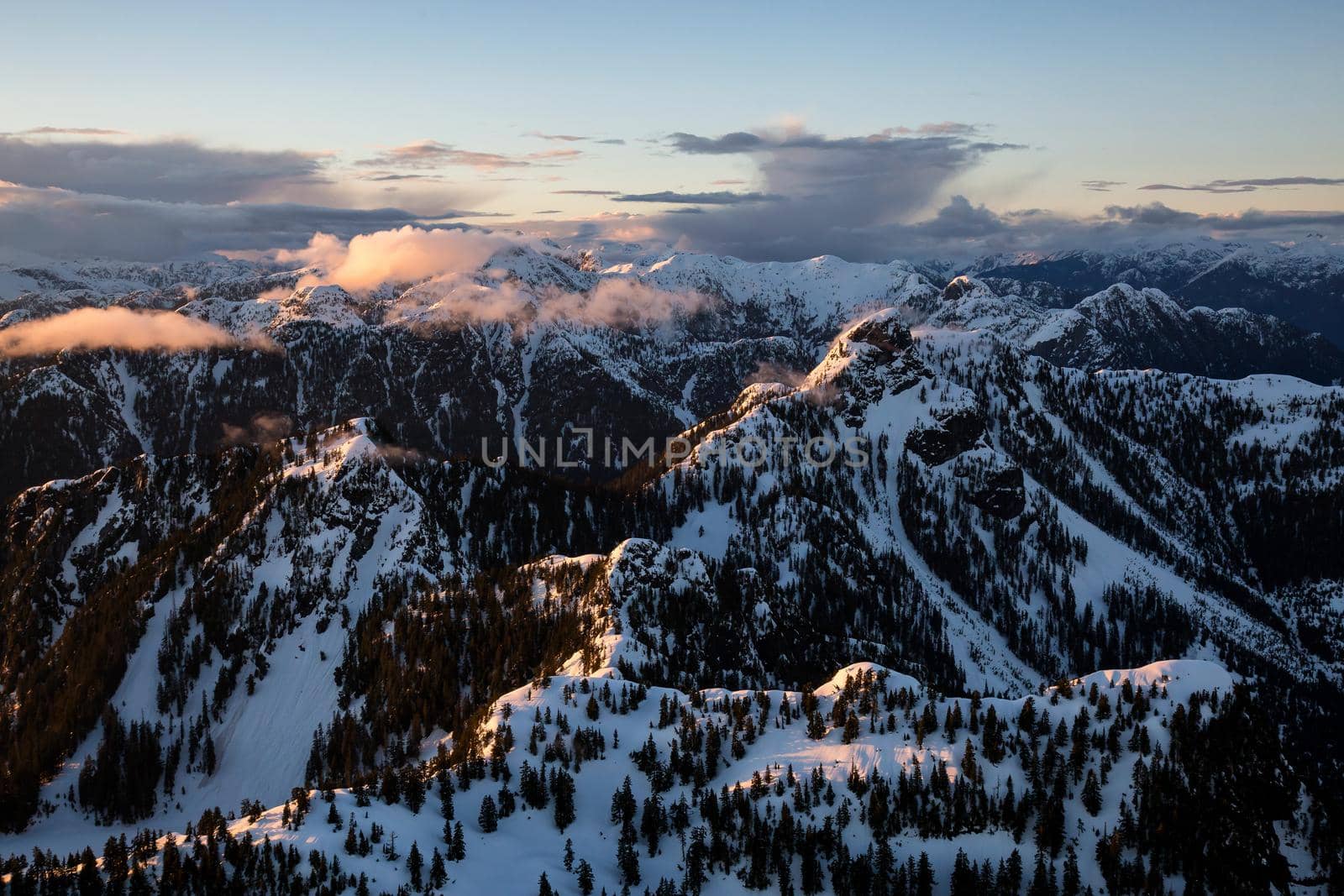 Aerial Landscape View of North Shore Mountains during a colorful cloudy sunset. Taken in Vancouver, British Columbia, Canada.