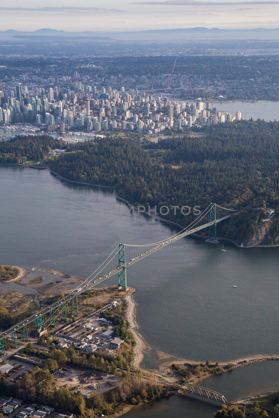 Aerial view on Lions Gate Bridge, Stanley Park, and Downtown Vancouver, during a sunny day.