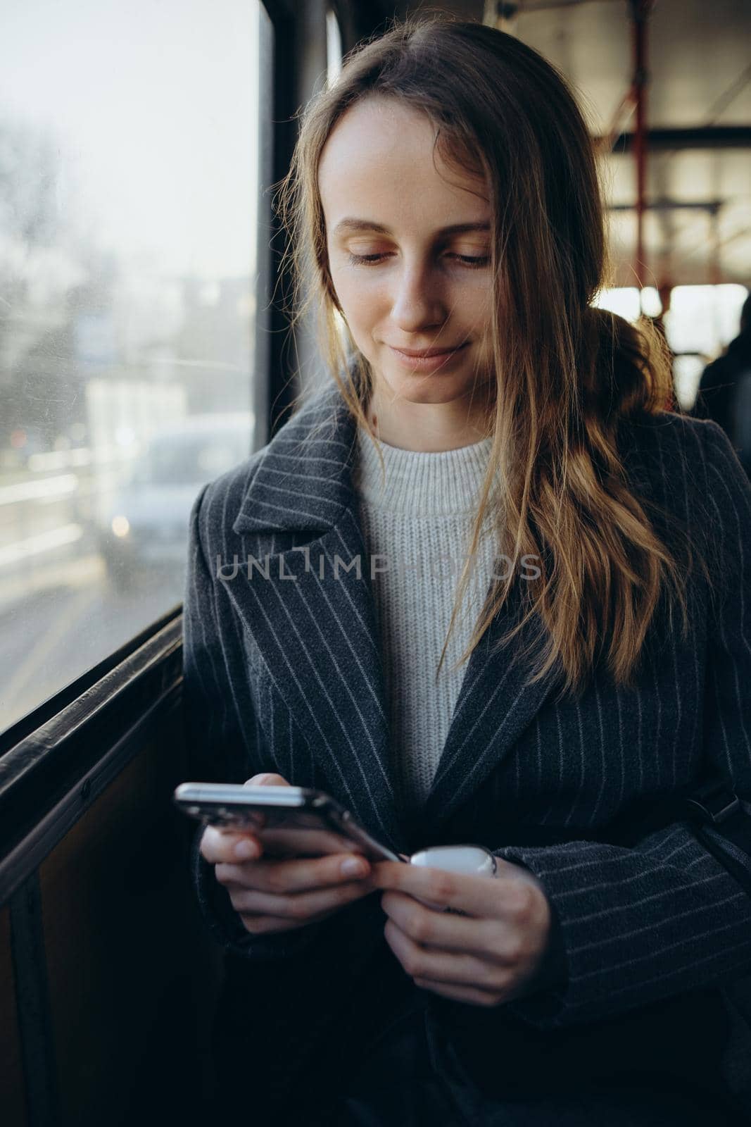 Young woman sadly looking out bus window, wear earphones by Symonenko