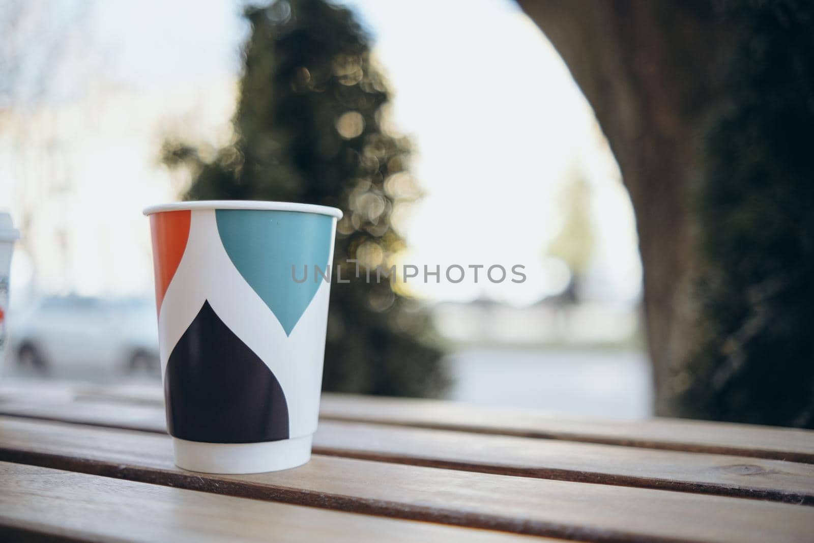 Paper cup with tea coffee drink on a wooden table against the background plant and a green wall. Zero West Concept.