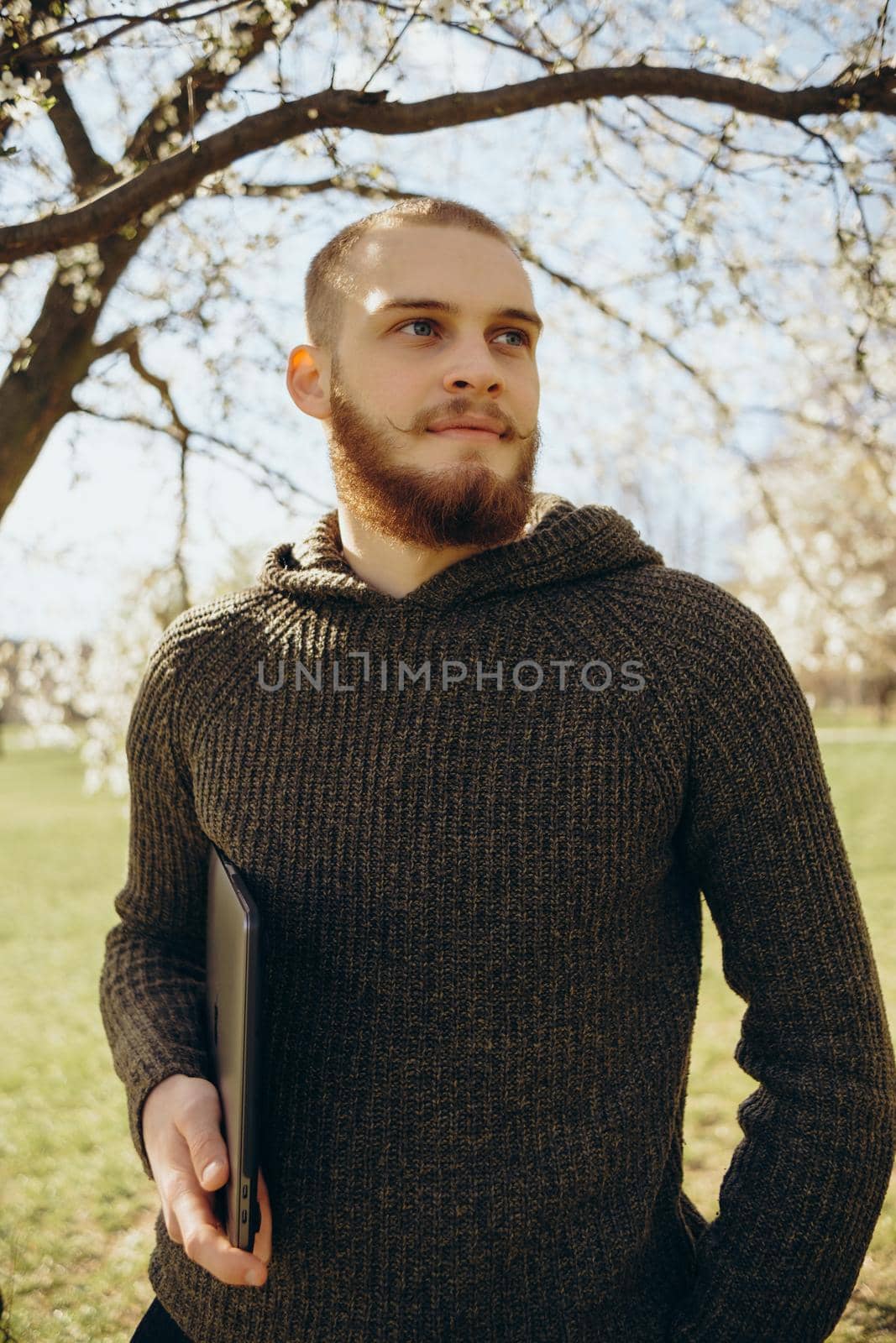 happy young man outdoors looking at the camera with laptop