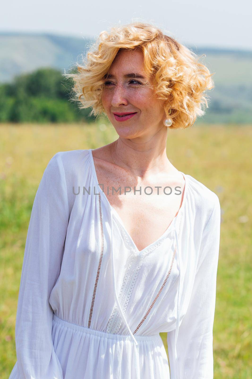 Beautiful blonde woman with short curly hair outdoors. by Smile19