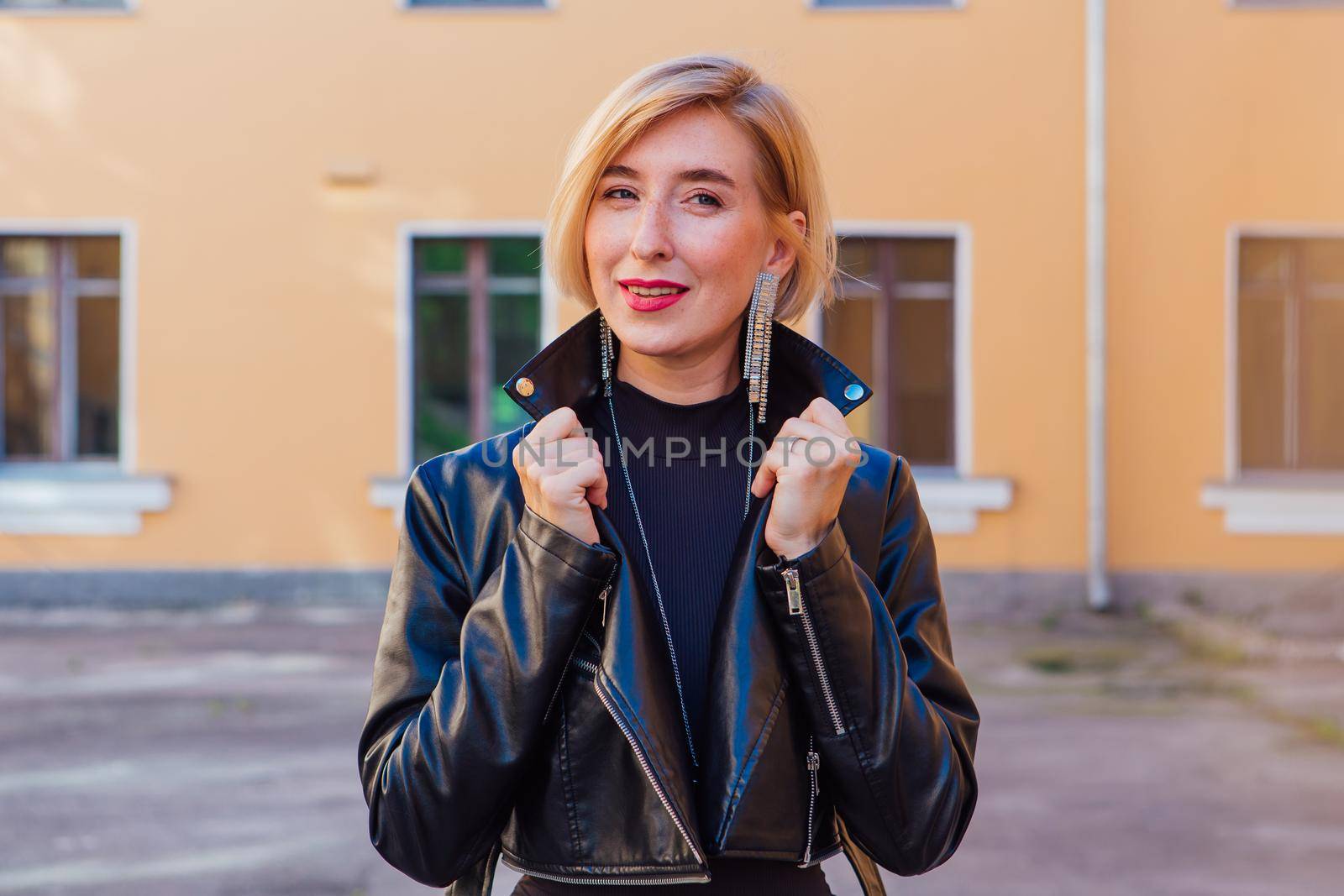 Street fashion concept - closeup portrait of a pretty girl wearing leather jacket outdoors.