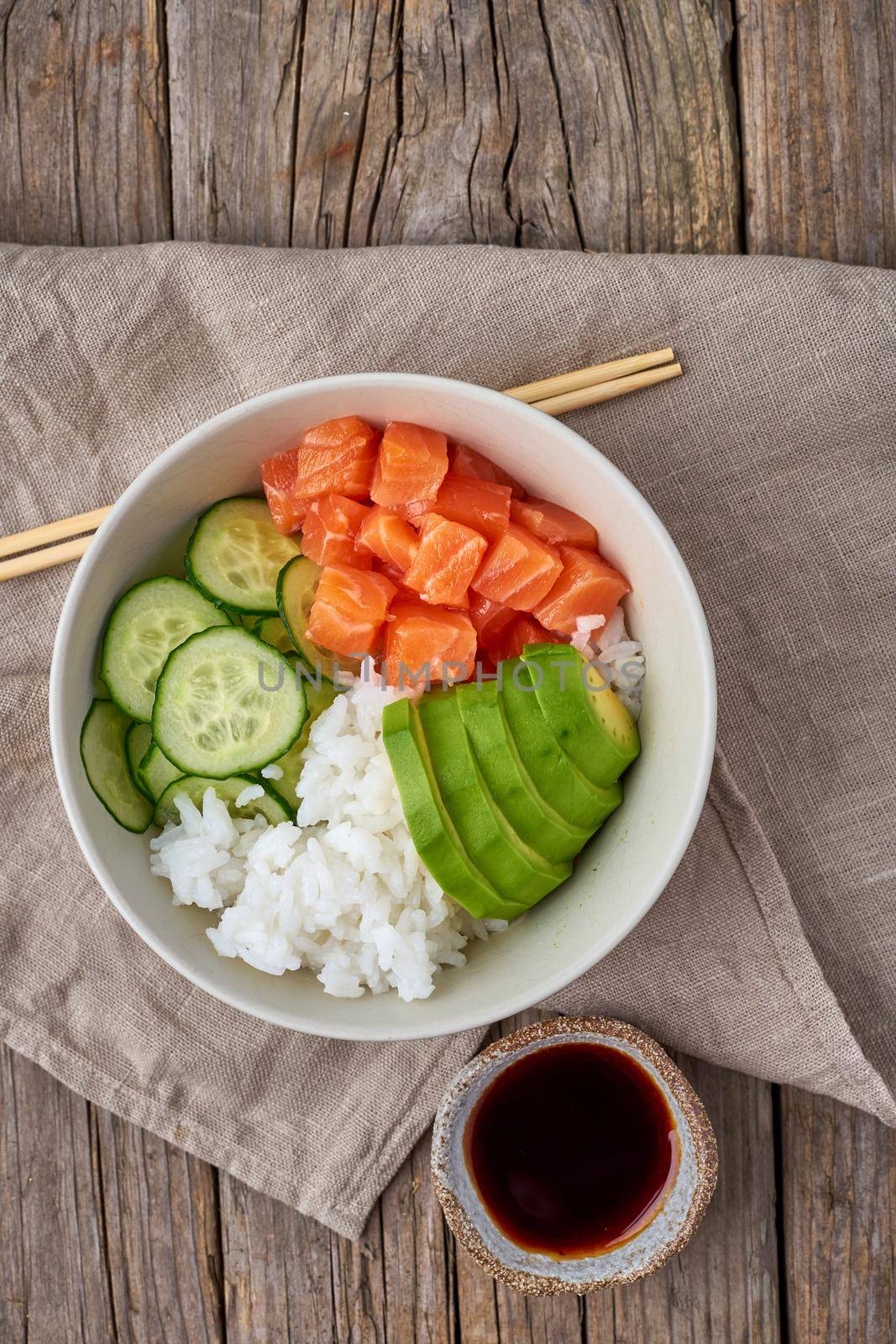 salmon poke bowl with fresh fish, rice, cucumber, avocado by NataBene