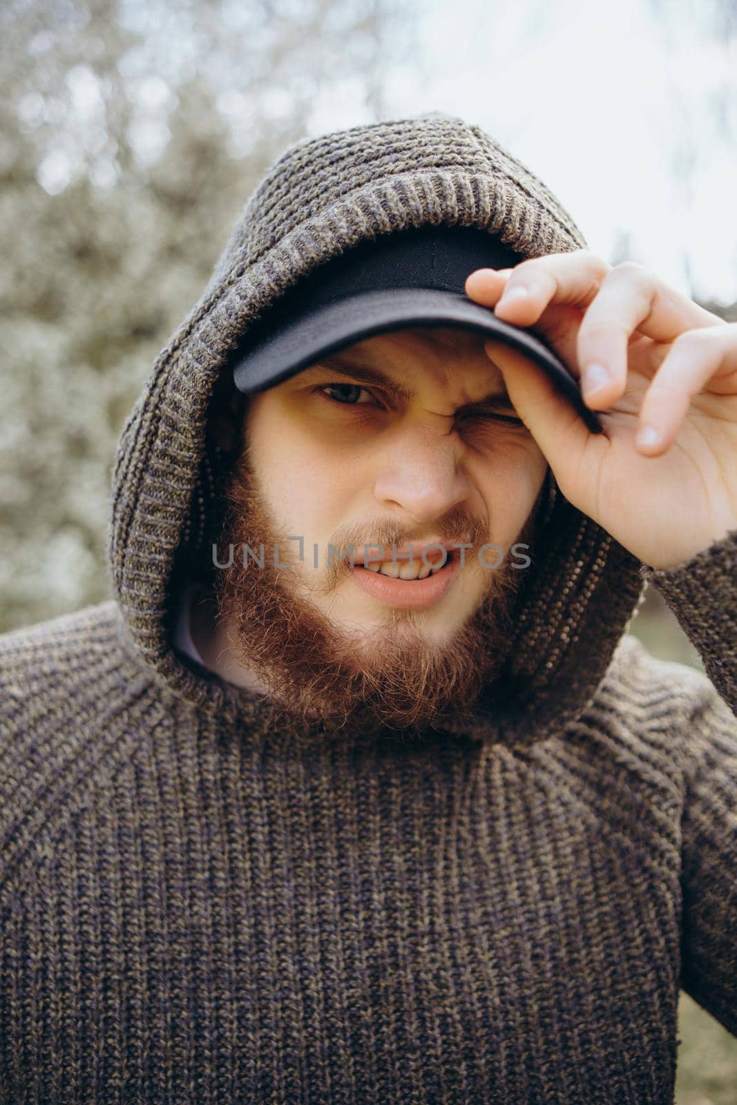 Headshot of a man wearing a brown hooded top with an intense stare at the park.