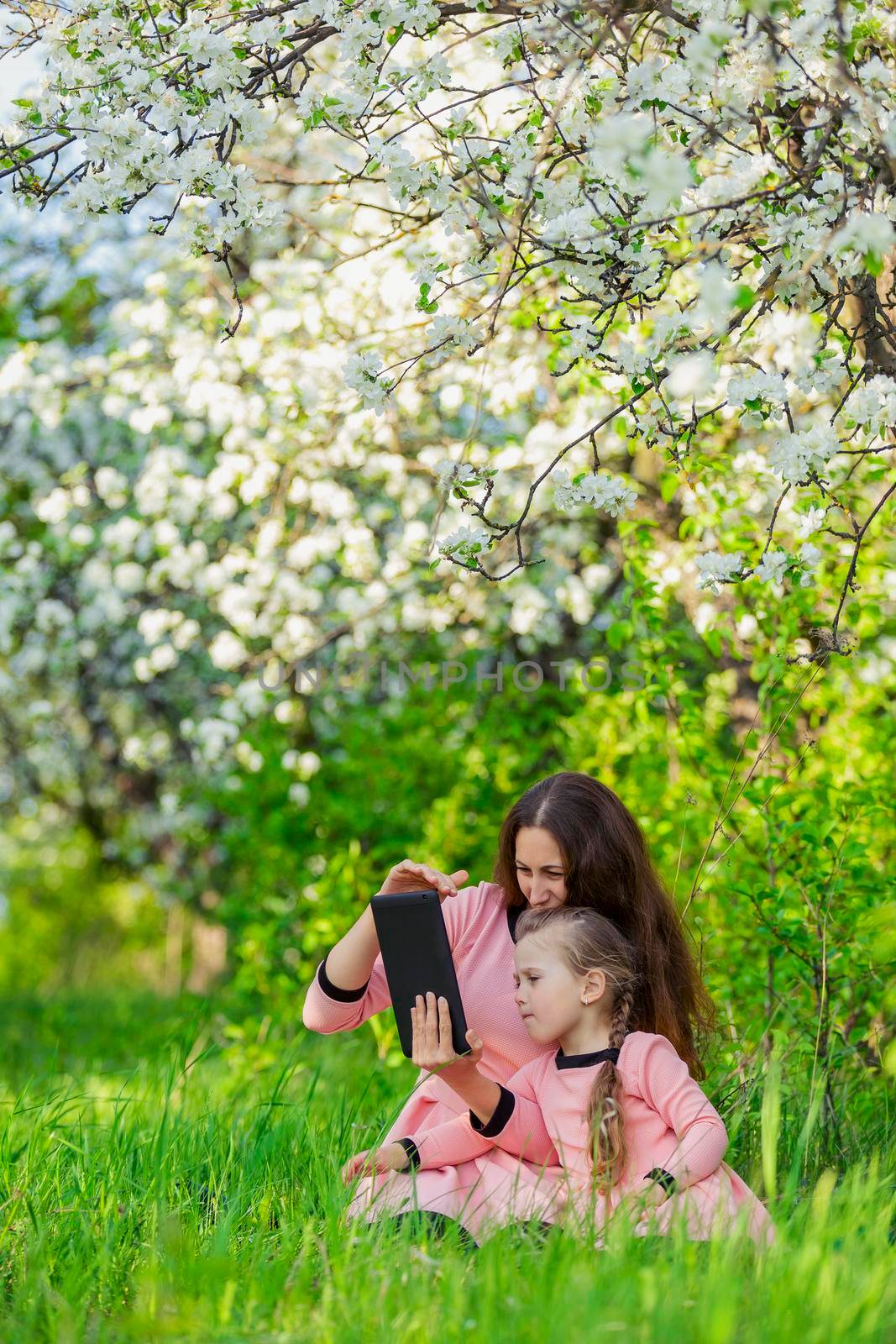 mother and daughter take a selfie using a tablet in nature