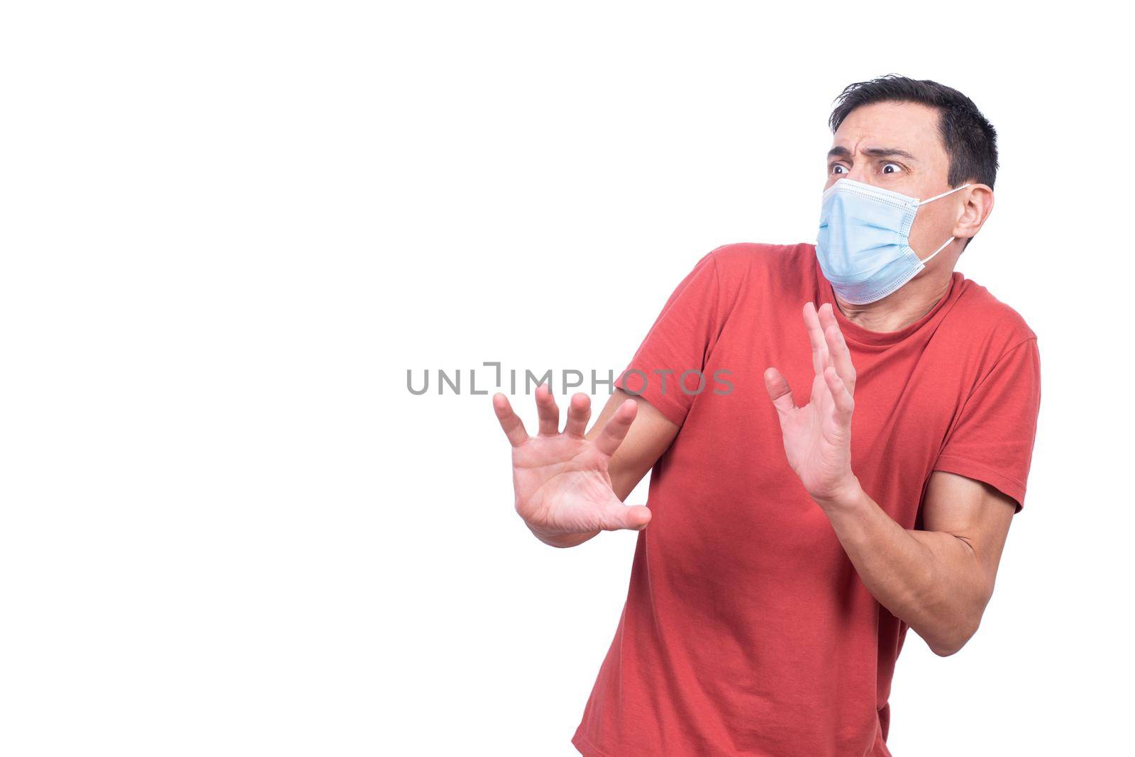 Fearful male in medical mask looking away with frightened face expression isolated on white background in studio during COVID pandemic