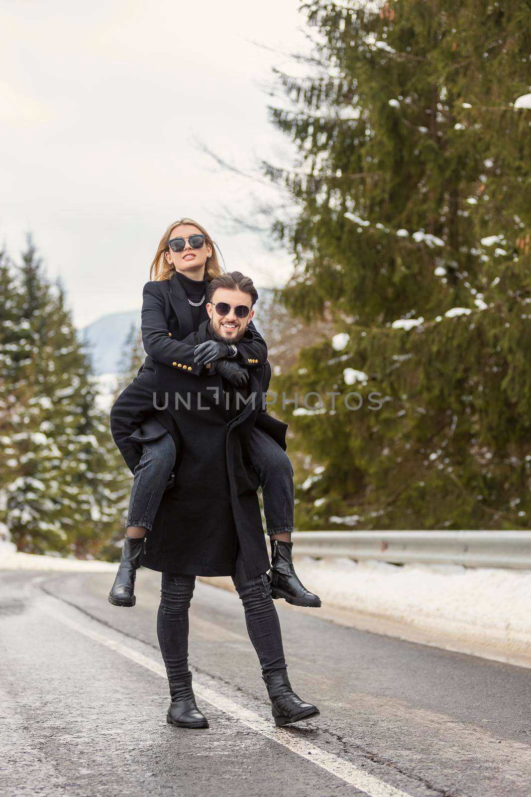 a guy with a girl on his back are walking on the road
