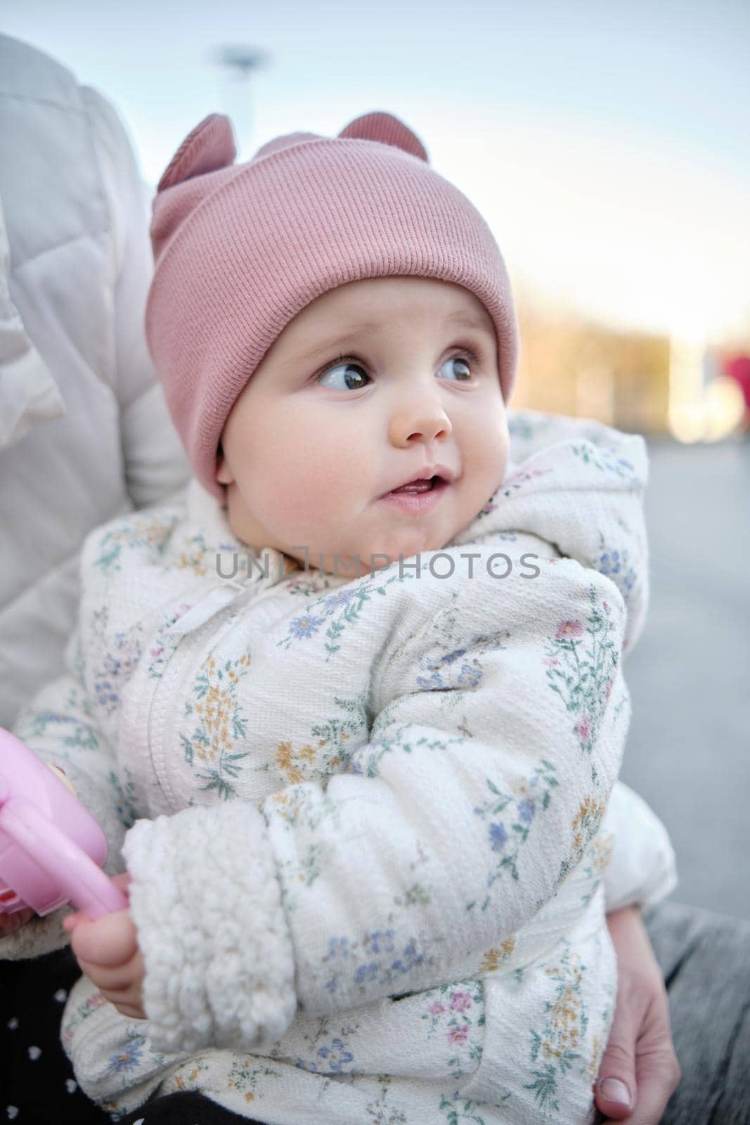 Mom holds the baby and plays with him on the street. Six month old baby in a hat, jacket and pants.