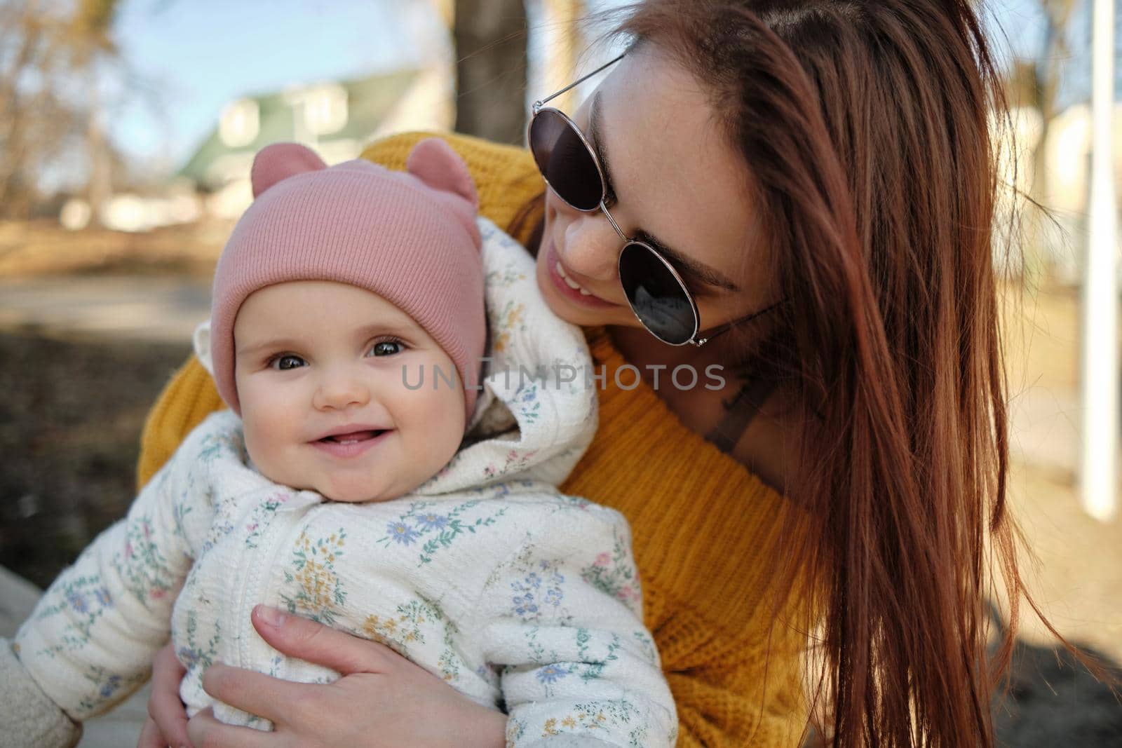 Mother holding baby smiling to camera. Real life authentic casual mom looking to camera holding infant