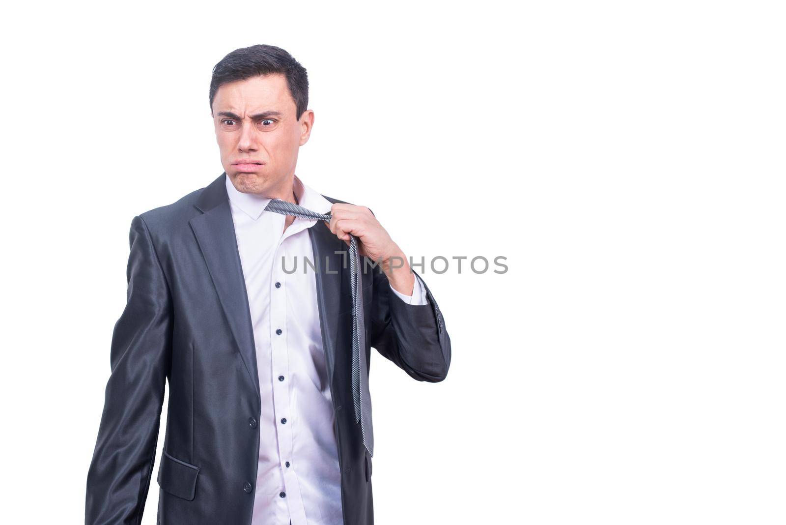 Tired male entrepreneur in formal wear taking off tie and looking away while standing isolated on white background in studio