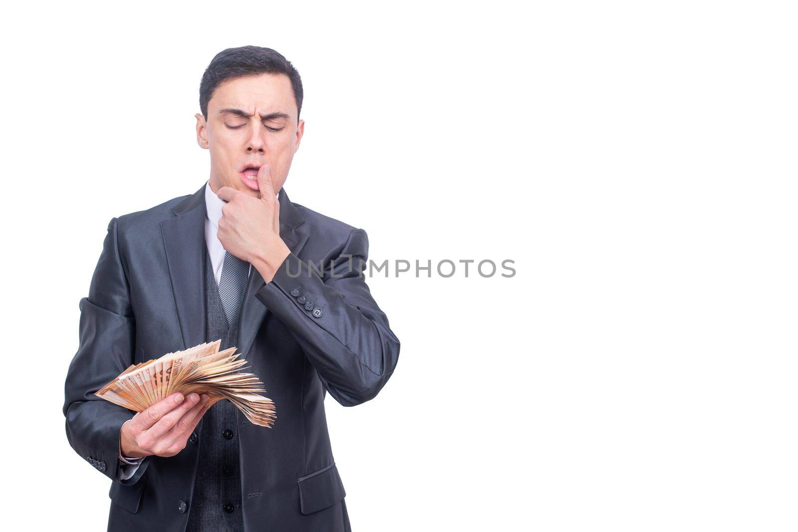 Successful millionaire male entrepreneur in elegant suit counting bunch of money while standing isolated on white background in light studio