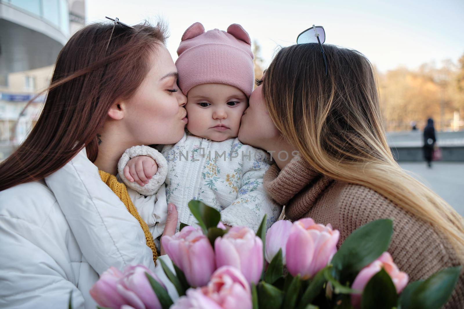 Mothers kissing their happy laughing child on both by Symonenko