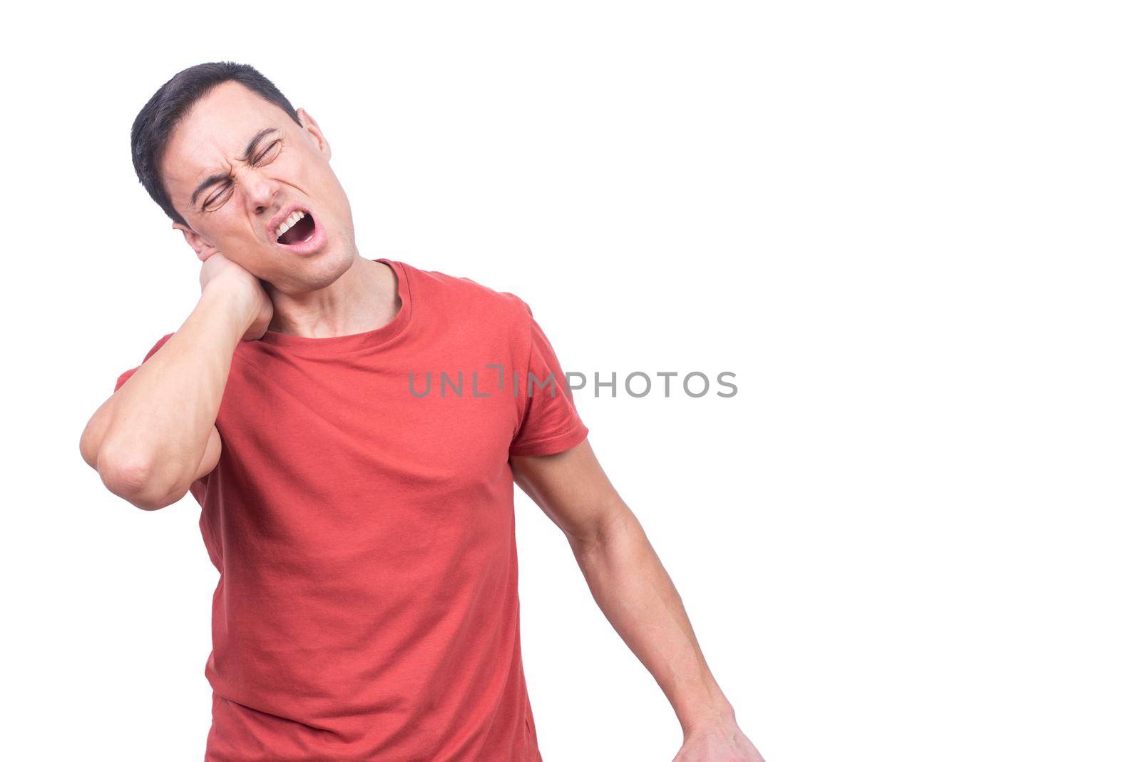 Brunet with closed eyes and opened mouth wearing red t shirt and massaging stiff neck while standing on white background