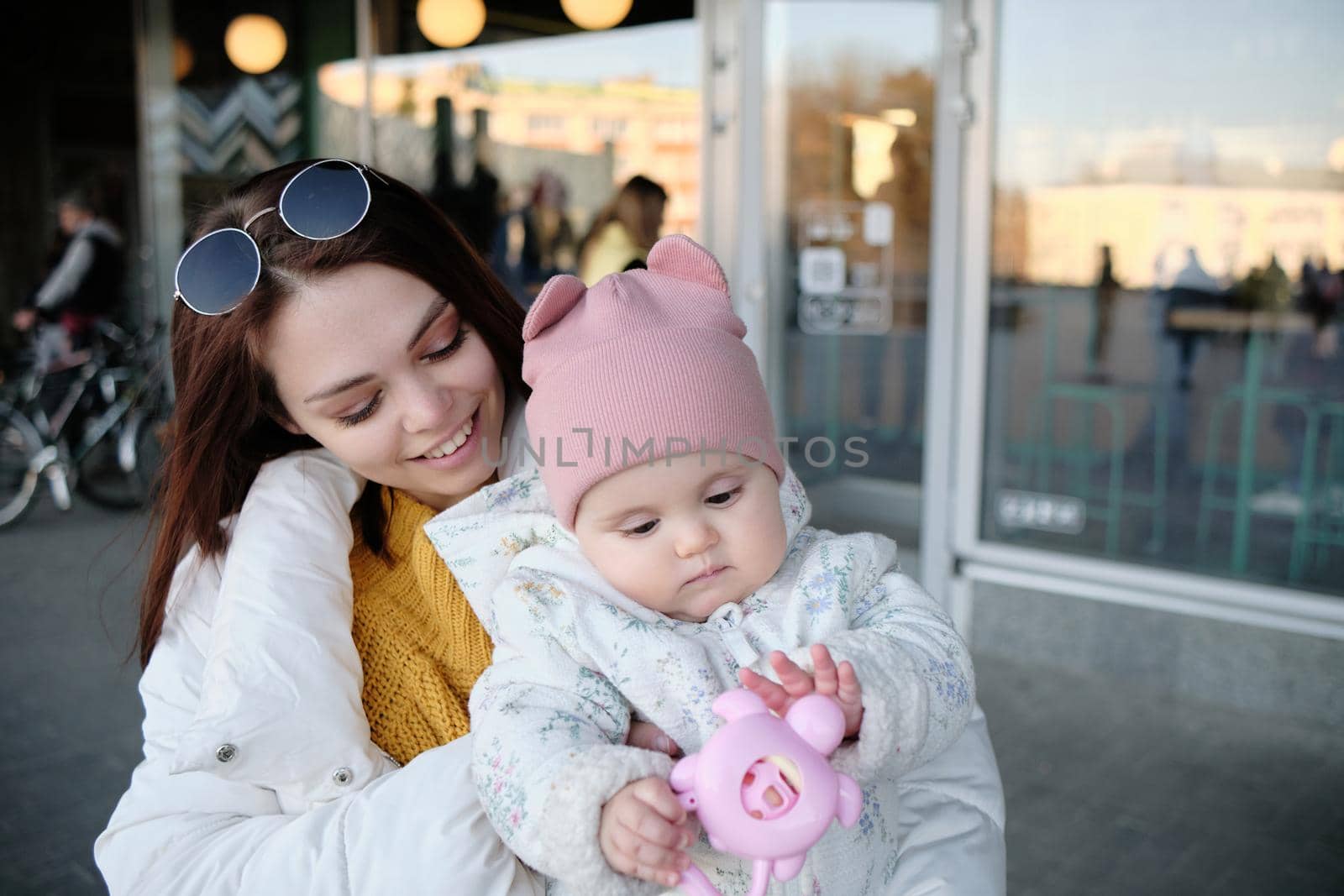 Mother holding baby smiling to camera. Real life authentic casual mom looking to camera holding infant