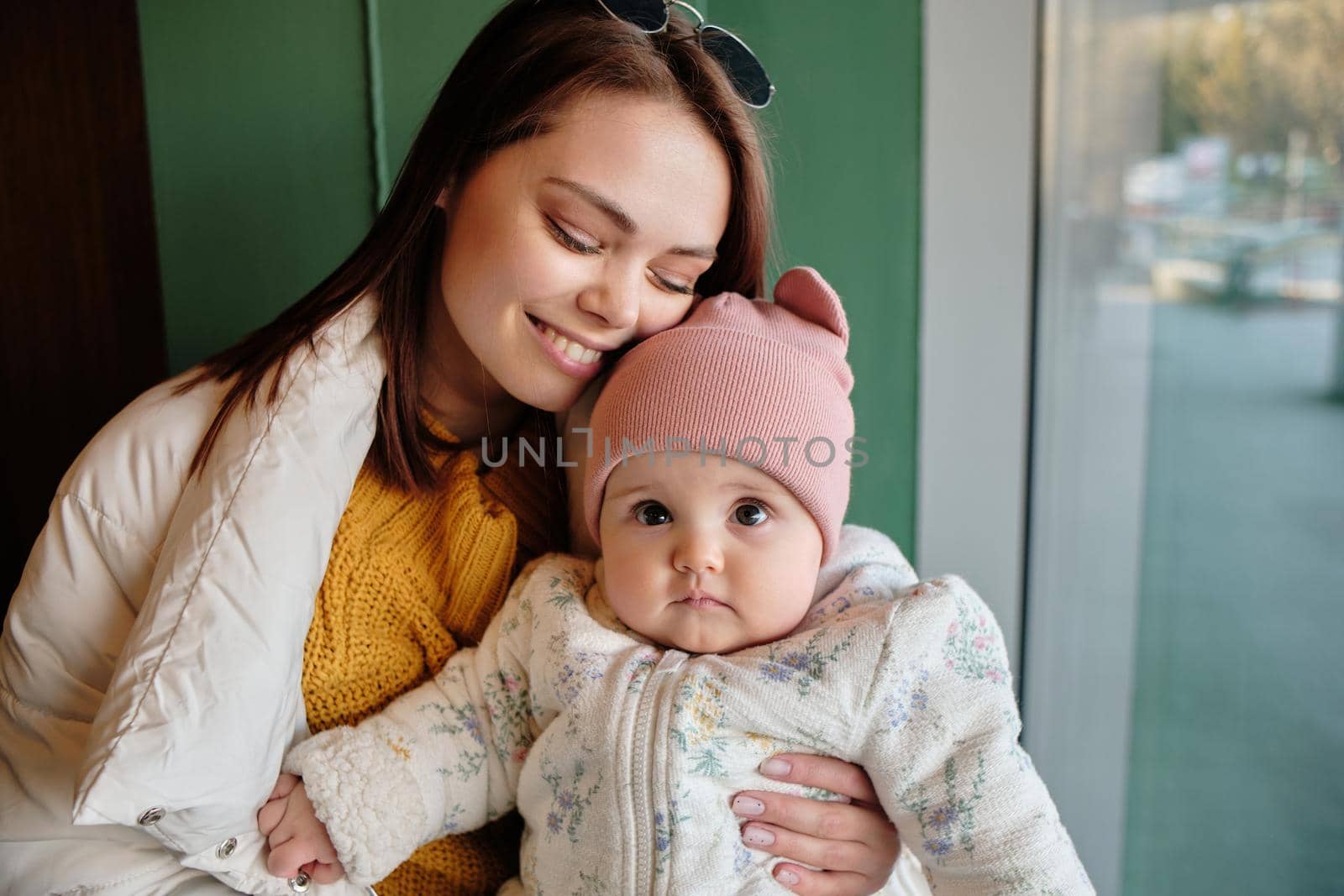 Mother holding baby smiling to camera. Real life authentic casual mom looking to camera holding infant