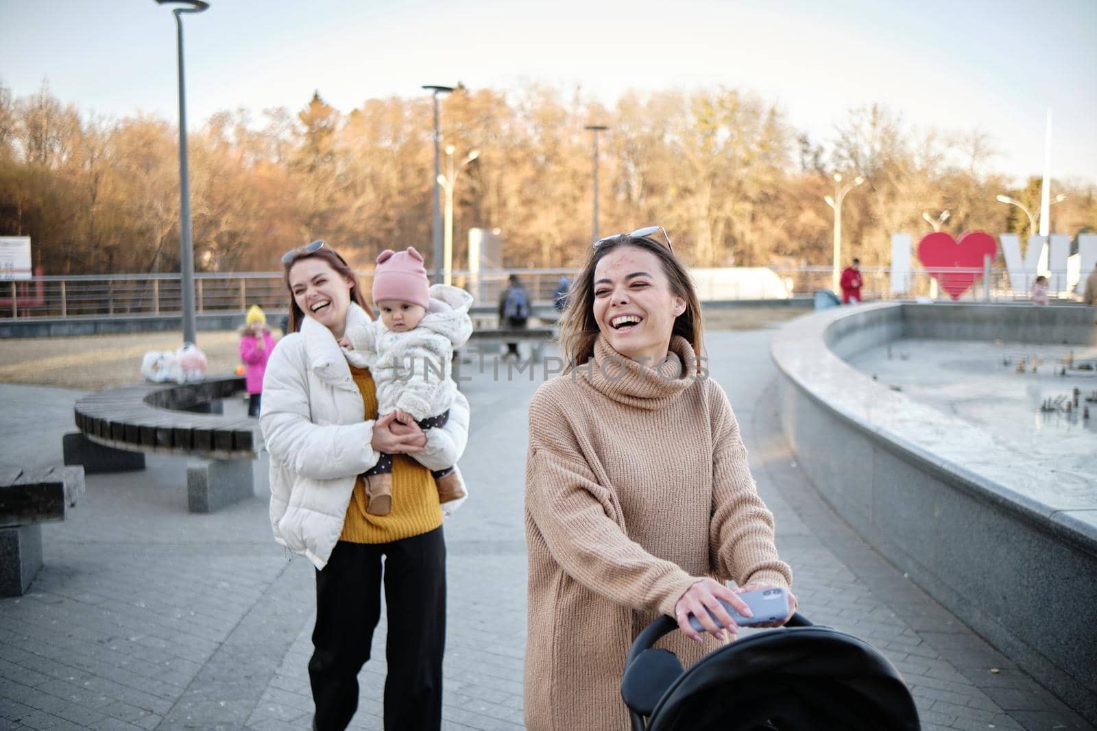 Smiling multi-ethnic lesbian couple walking outdoors with little son by Symonenko