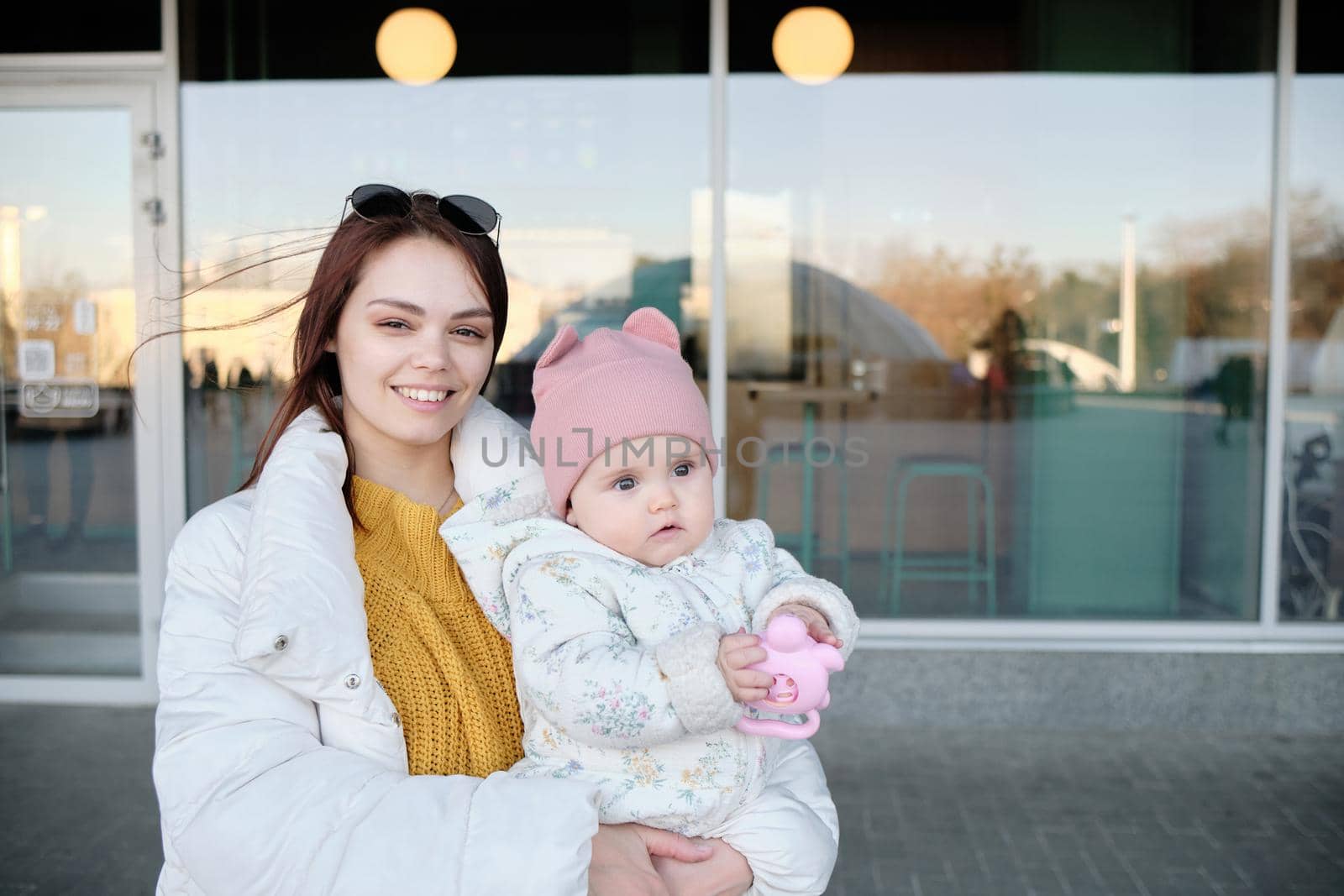 Mother holding baby smiling to camera. Real life authentic casual mom looking to camera holding infant