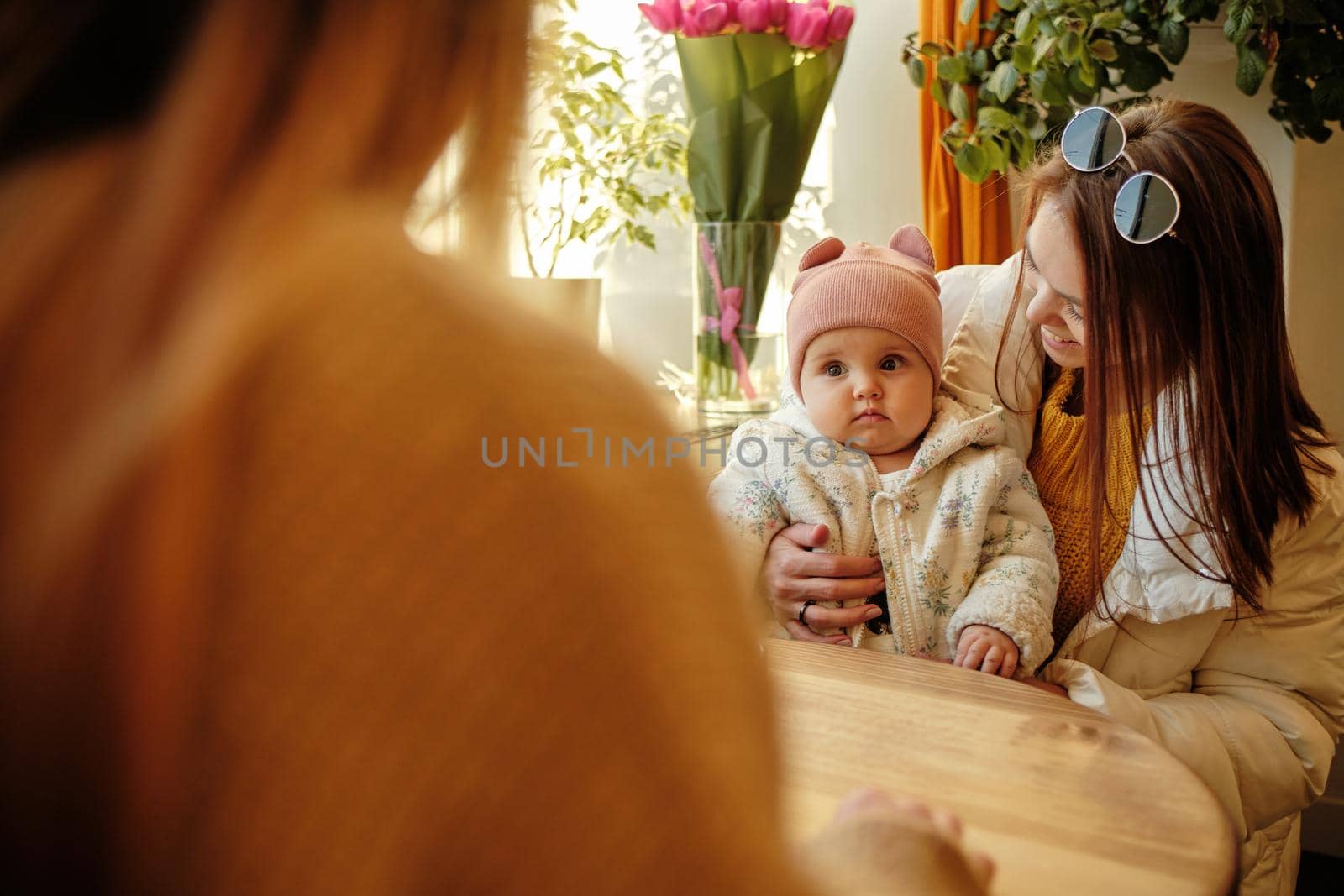 young and pretty mother sitting at the cafe with her little daughter sunny