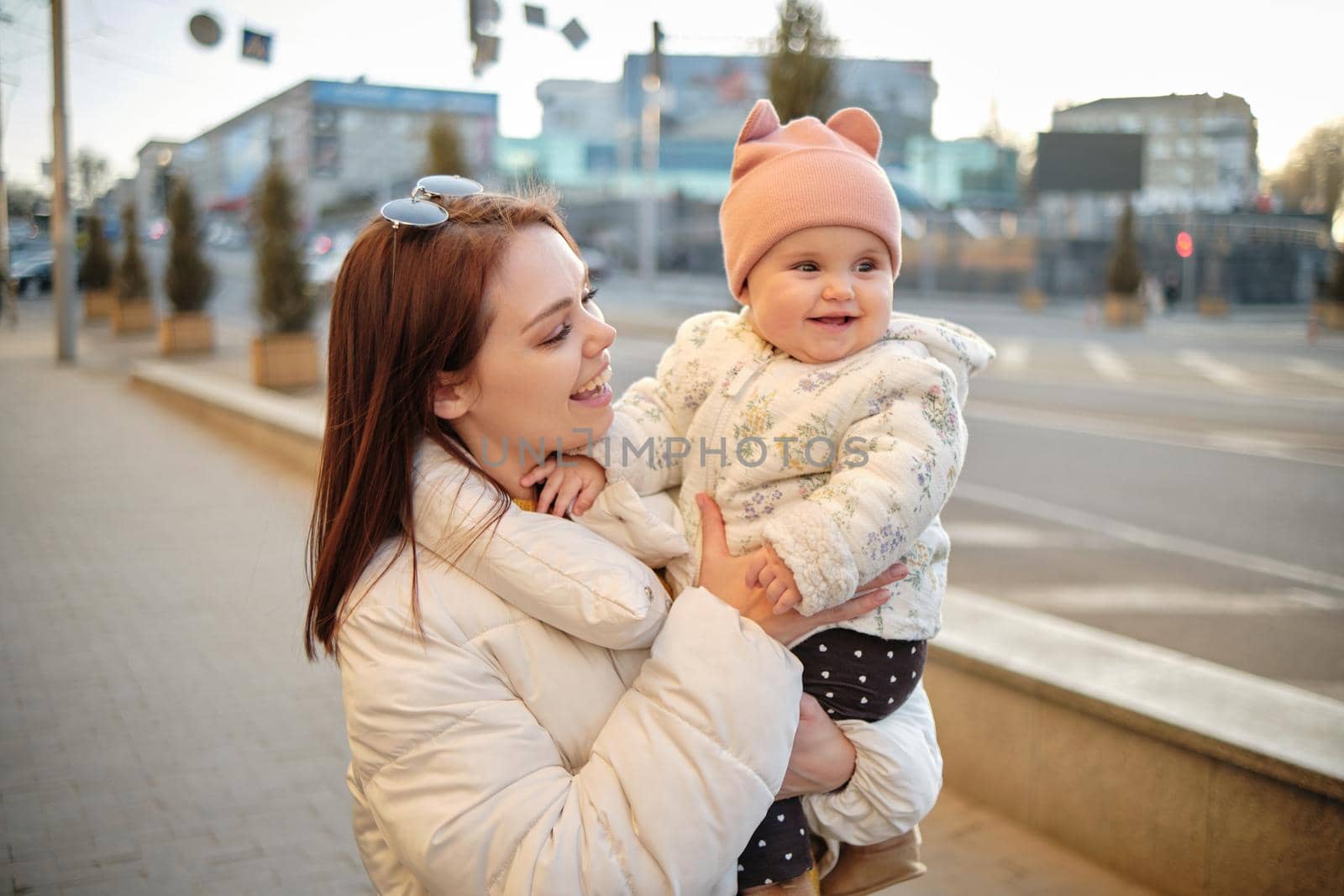 Mother holding baby smiling to camera. Real life authentic casual mom looking to camera holding infant