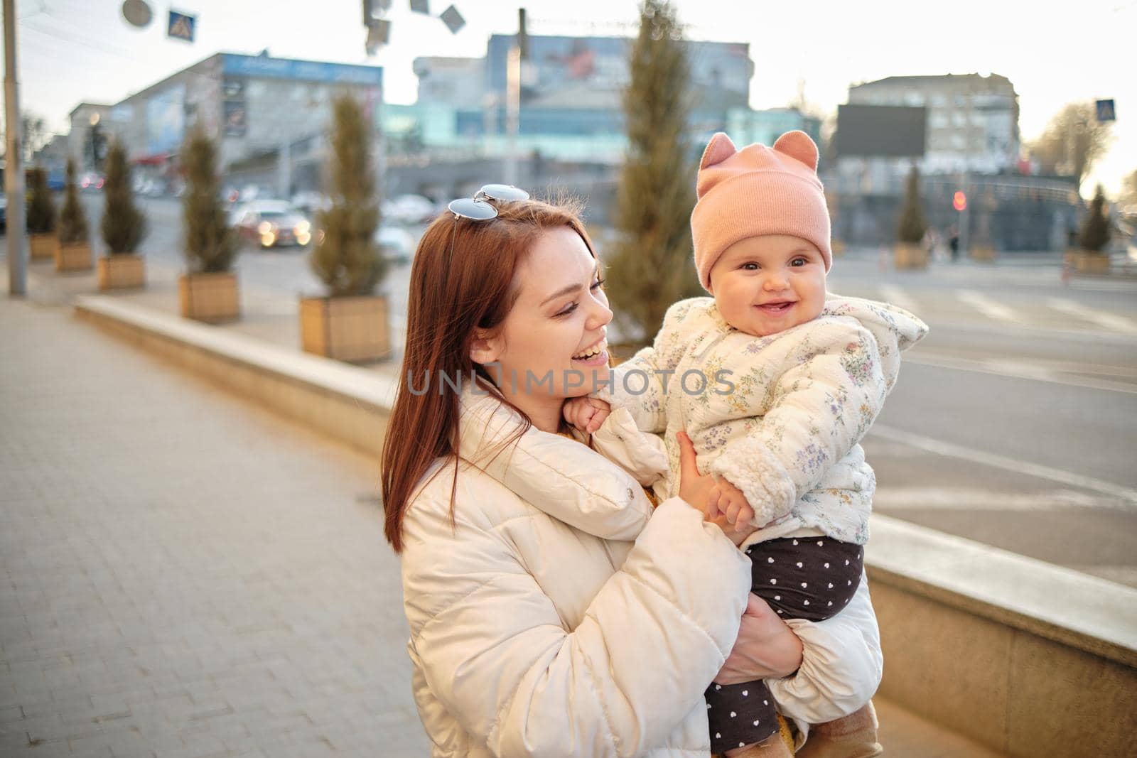 Mother holding baby smiling to camera. Real life authentic casual mom looking to camera holding infant