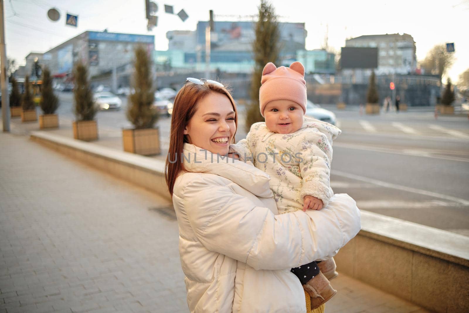 Mother holding baby smiling to camera. Real life authentic casual mom looking to camera holding infant