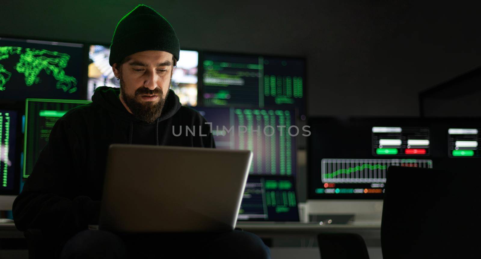 Horizontal banner. Hacker hacking security firewall in basement hideout. Multiple screens background. Copy space. by Hoverstock
