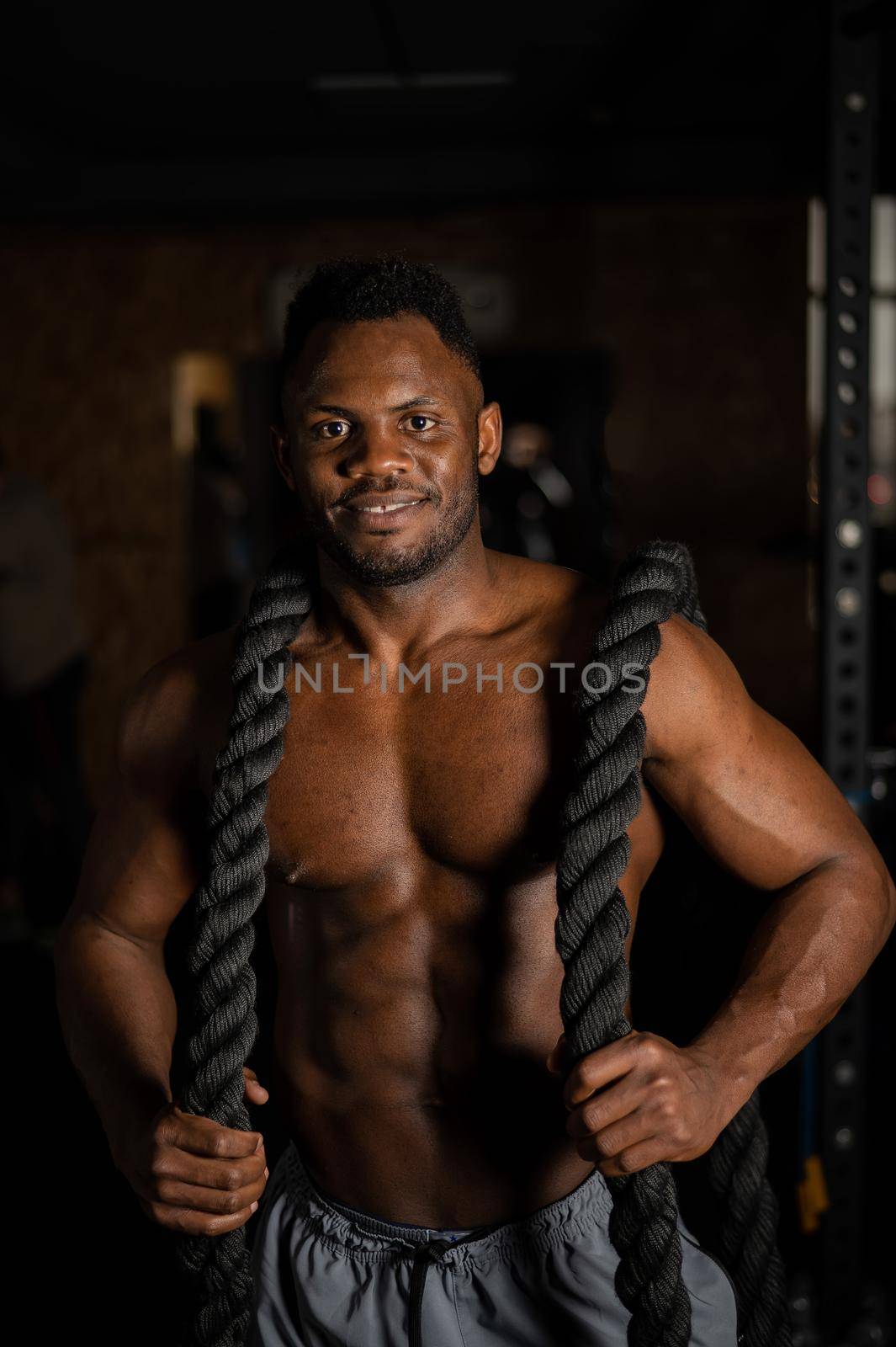 Muscular african american man posing with rope in gym. by mrwed54