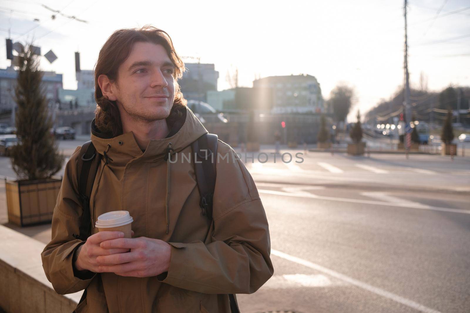 Happy smiling businessman going to the work with coffee cup and using modern smartphone outdoors, successful employer using cellphone while on break outside at sunny day near his office