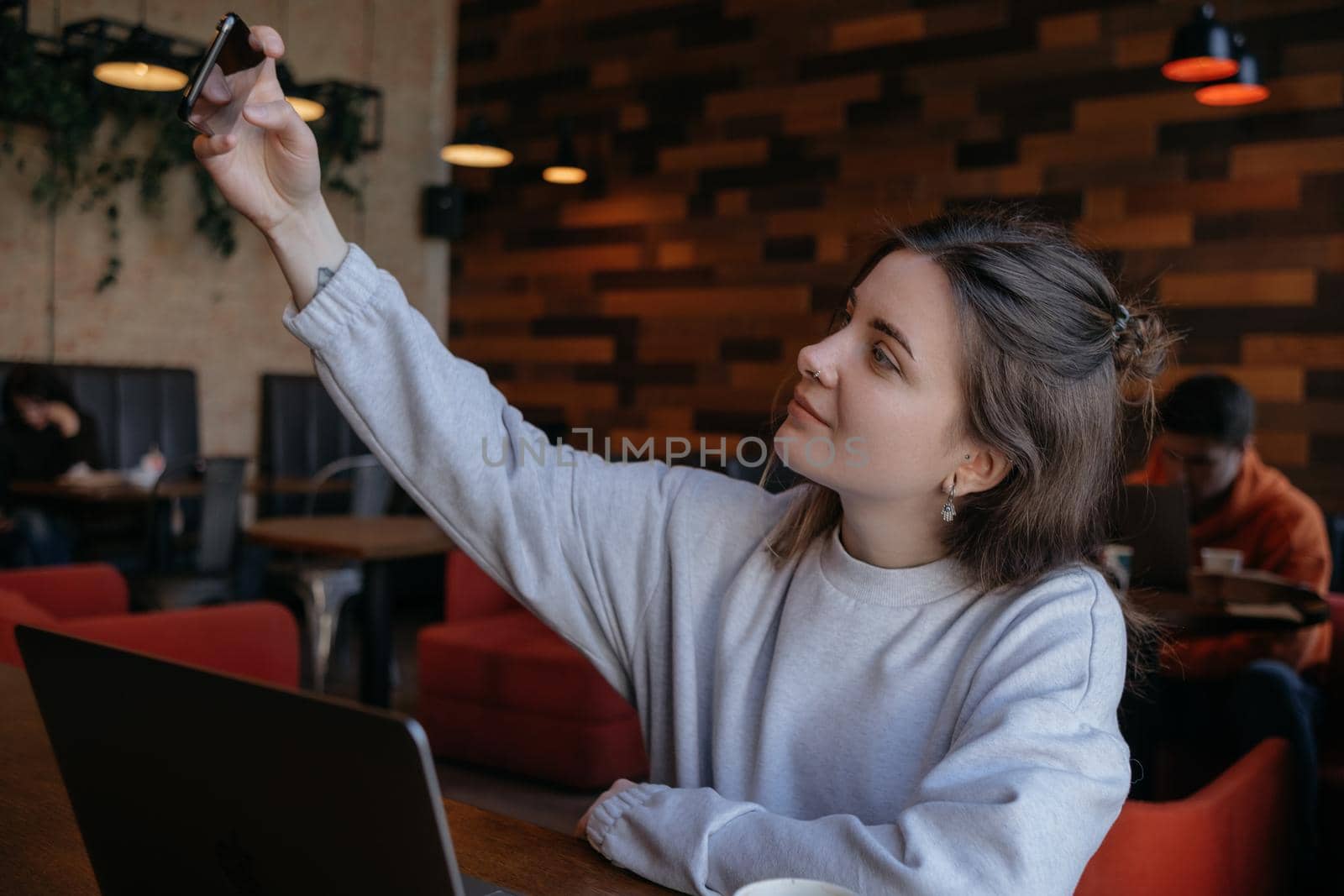 Smiling woman sitting on kitchen sofa talking by videocall dating online looking at phone. Video blogger vlogger recording vlog at home. Lifestyle vlogging concept, head shot portrait
