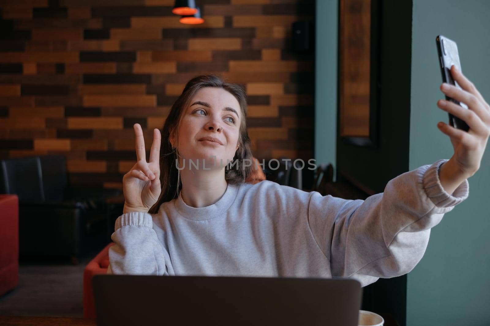 Smiling woman sitting on kitchen sofa talking by videocall dating online looking at phone. Video blogger vlogger recording vlog at home. Lifestyle vlogging concept, head shot portrait