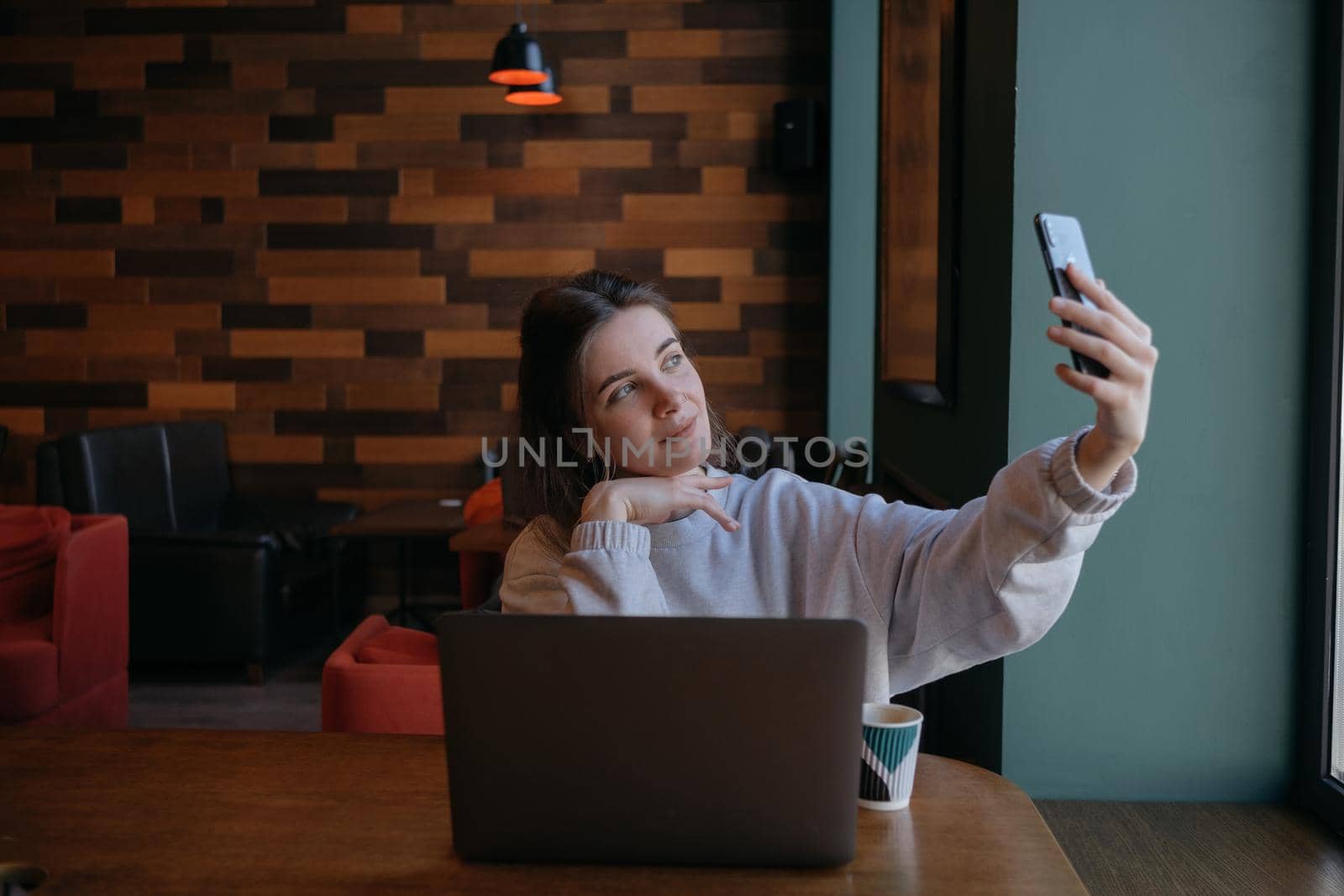 Smiling woman sitting on kitchen sofa talking by videocall dating online looking at phone. Video blogger vlogger recording vlog at home. Lifestyle vlogging concept, head shot portrait