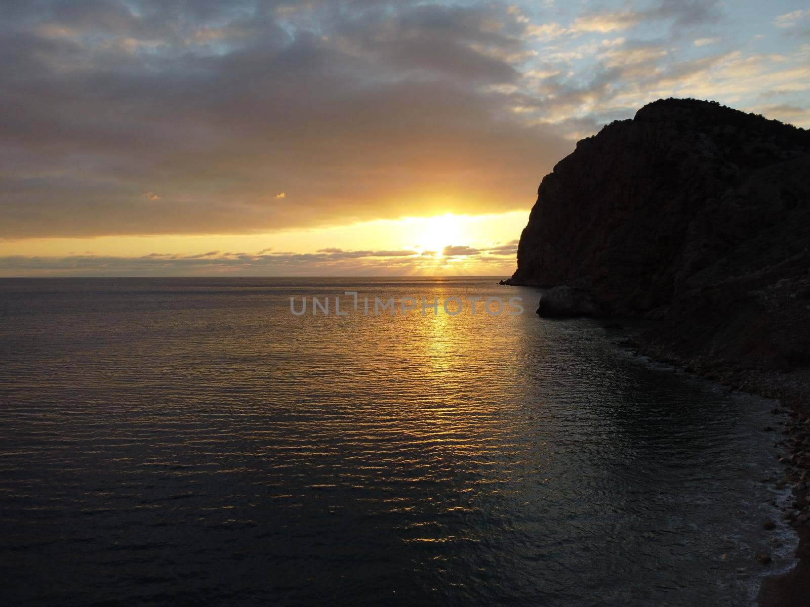 Aerial panoramic view of beautiful sunset above calm azure sea and volcanic rocky shores. Sun glare, small waves on the water surface. Horizon. Nobody. No people. Never-ending beauty of nature by panophotograph