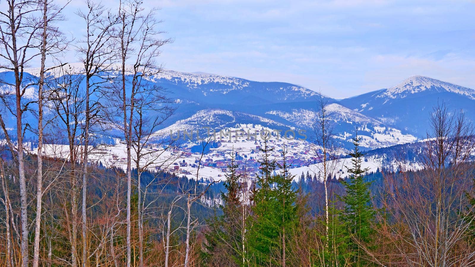 a low area of land between hills or mountains, typically with a river or stream flowing through it.Village in a wooded mountain valley in winter.