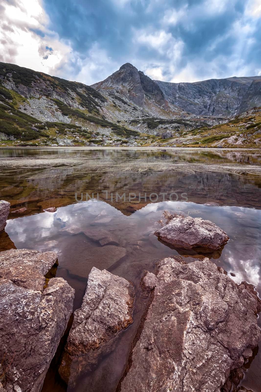 beauty day landscape on the mountain lake with rocks at the front. Vertical view