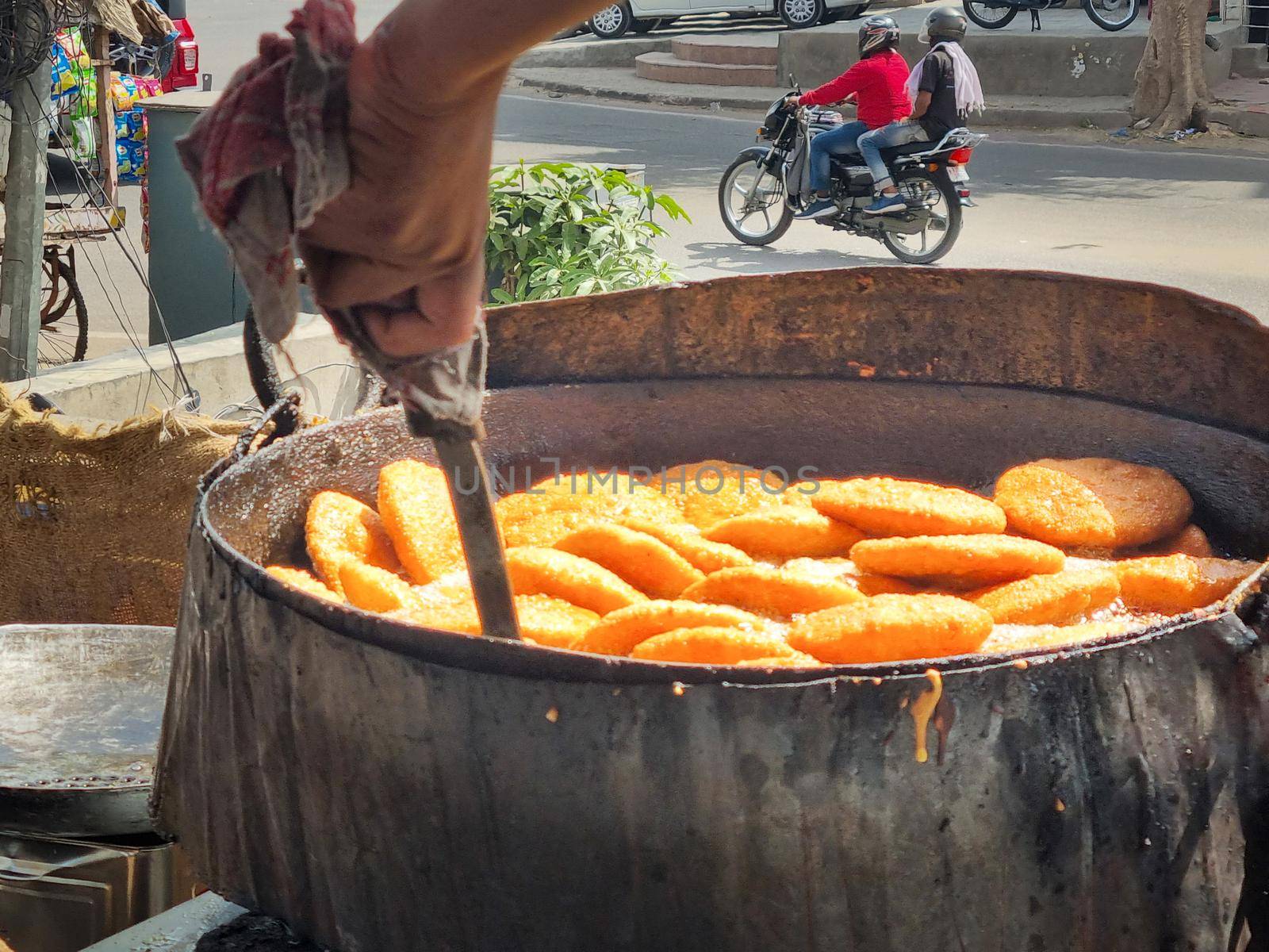 close up of shop cook deep frying many kachori in boiling oil making streetfood snack that is popular throughout rajasthan jaipur India for it's spicy flavor by Shalinimathur