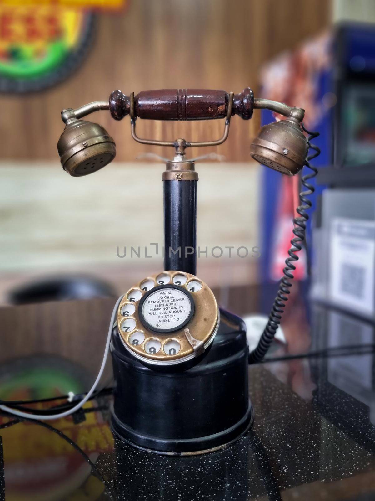 vintage antique phone with long neck to hold receiver and rotary dial placed at an office restaurant counter in India by Shalinimathur