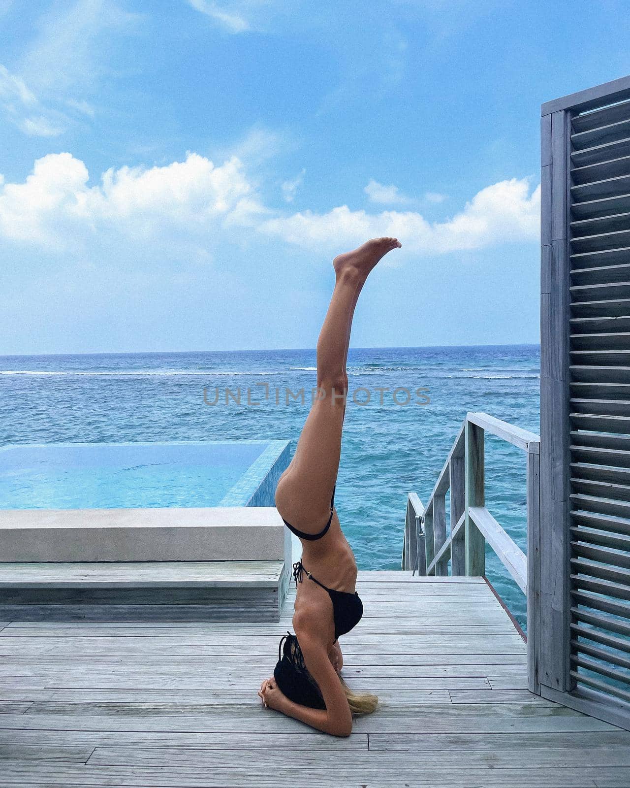 Beautiful slender woman in a swimsuit practicing yoga, Maldives, beautiful background, clean water, pool, sea and ocean.