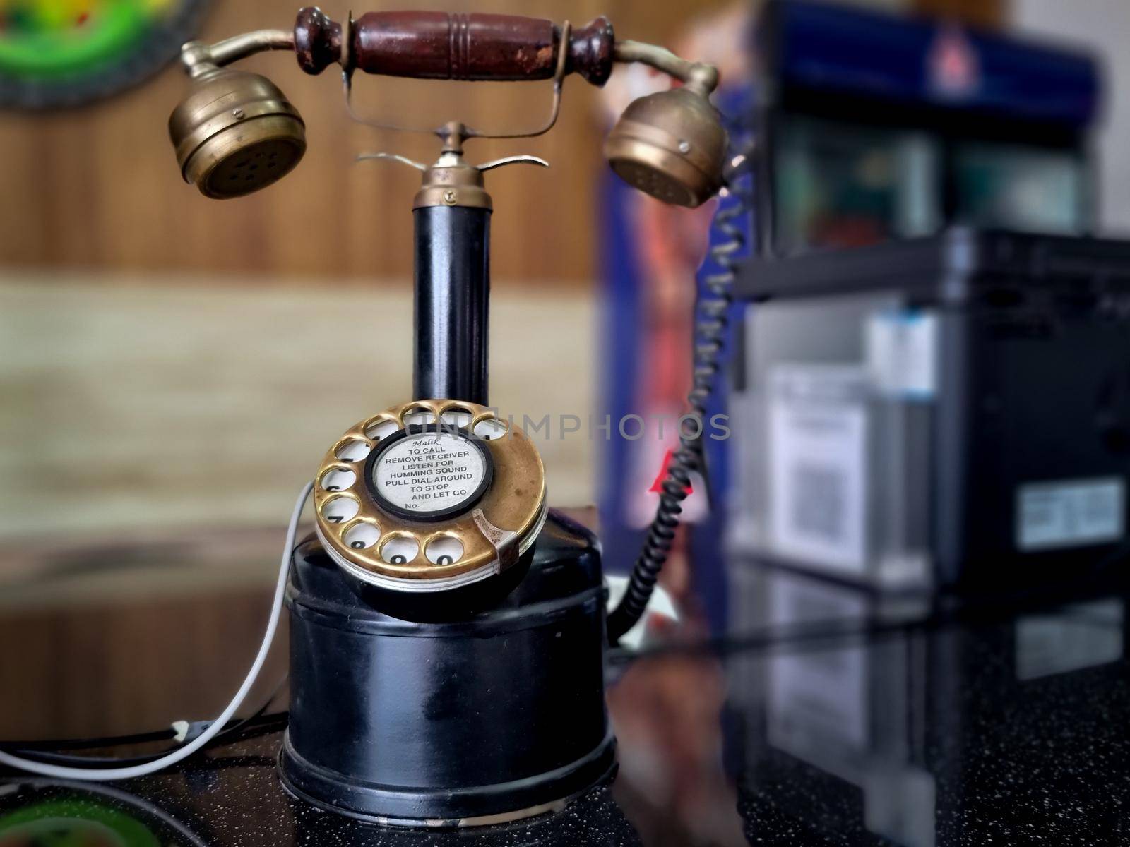 vintage antique phone with long neck to hold receiver and rotary dial placed at an office restaurant counter in India by Shalinimathur