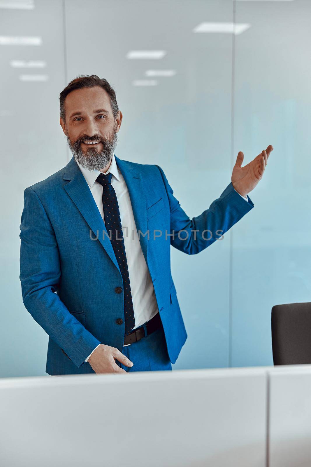 Caucasian handsome intelligence successful businessman in formal suit standing against white wall, copy space