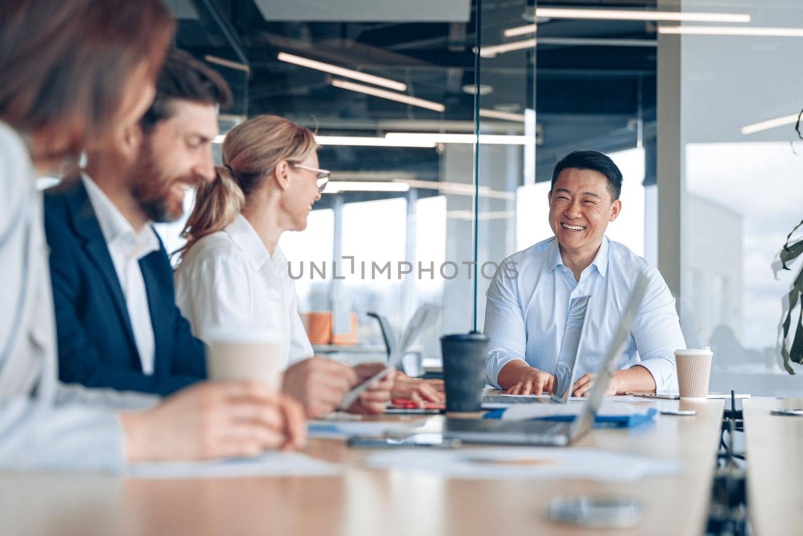 Workteam of young asian businessman working and communicating together in an modern office by Yaroslav_astakhov