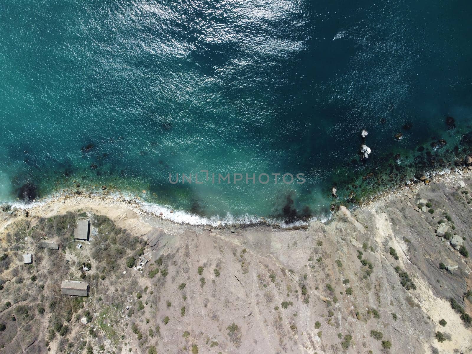 Aerial view on calm azure sea and volcanic rocky shores. Small waves on water surface in motion blur. Nature summer ocean sea beach background. Nobody. Holiday, vacation and travel concept by panophotograph