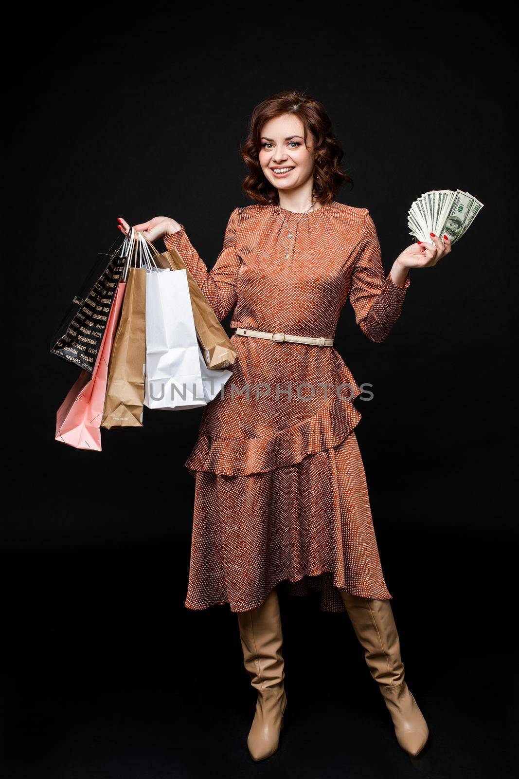 Beautiful young woman after shopping stands with a lot of packages and money in her hands by StudioLucky